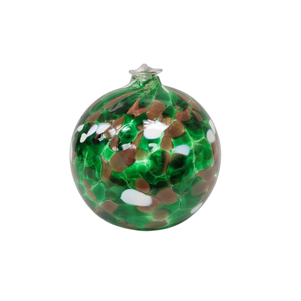 Round glass ball with flat base and wick with green, brown glitter and opaque white glass mosaiced around the entire surface on a transparent background.