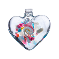 Clear glass heart with blue, pink, yellow and opaque white glass swirled in the centre on a transparent background.