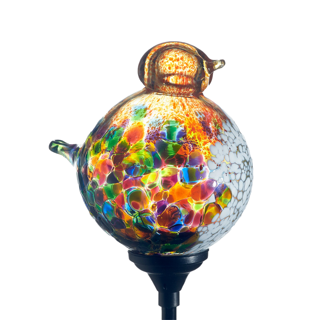 Glass bird with green, orange, lime, yellow, purple and pink mosaic along the surface, orange head and opaque white on chest with a black clip on a transparent background.