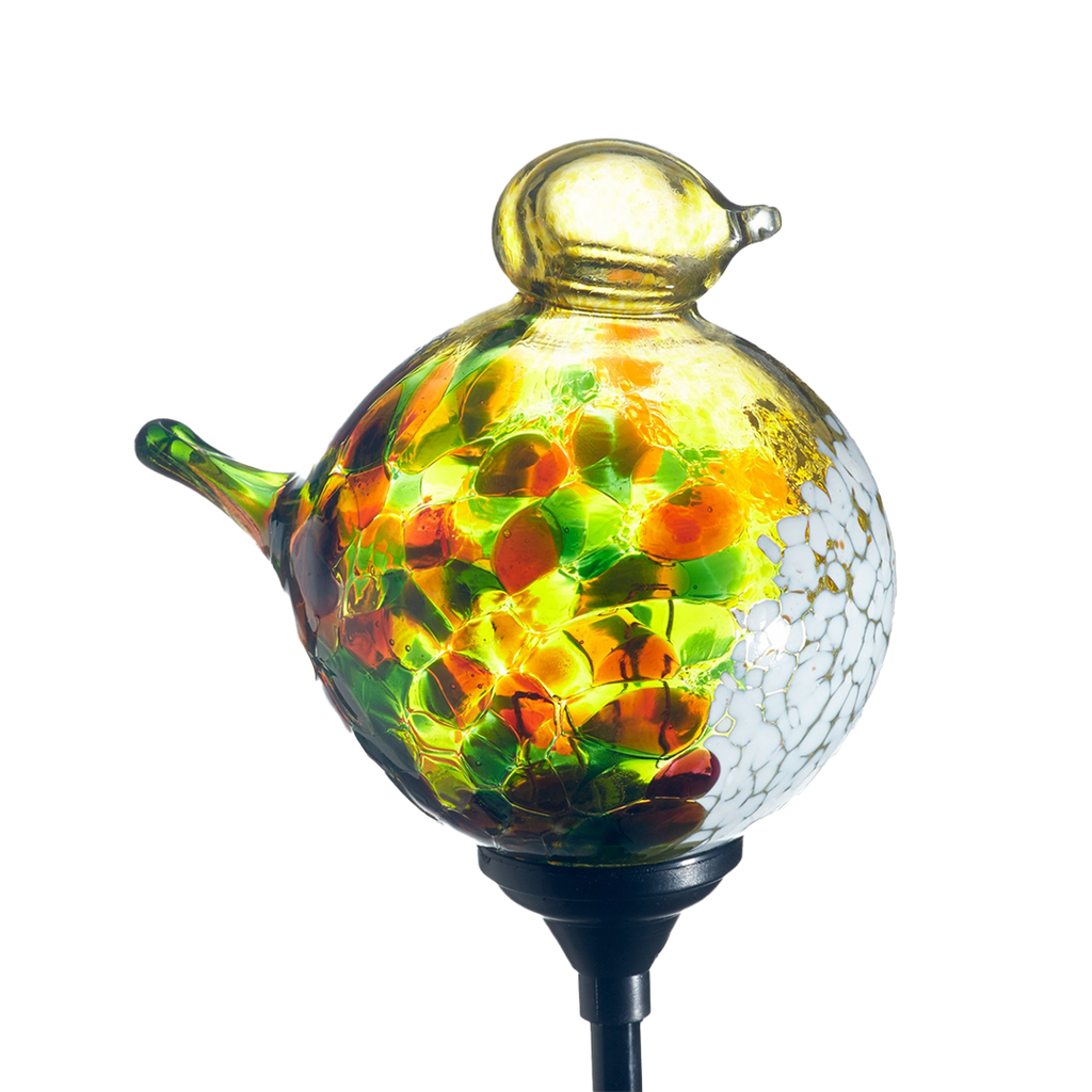 Glass bird with orange, yellow and green mosaic along the surface, yellow head and opaque white on chest with a black clip on a transparent background.