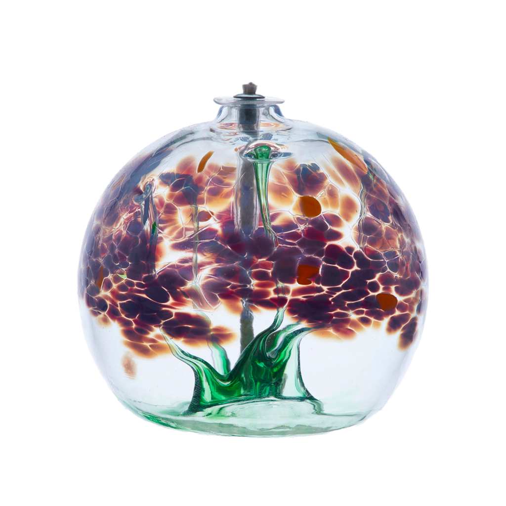 Clear glass orb with flat bottom and a wick with a green stem pulled from bottom to top to a canopy of purple opaque glass blossoms and orange centres on a transparent background.