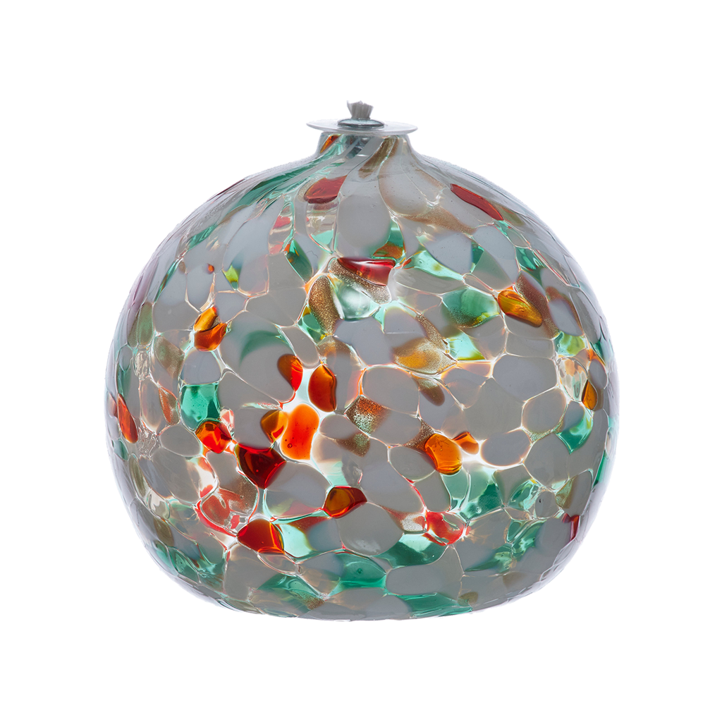 Round glass ball with flat base and wick with green, red and opaque white glass mosaiced around the entire surface on a transparent background.
