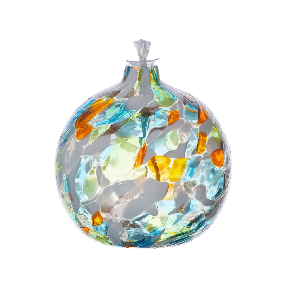 Round glass ball with flat base and wick with lime, orange, teal and opaque white glass mosaiced around the entire surface on a transparent background.