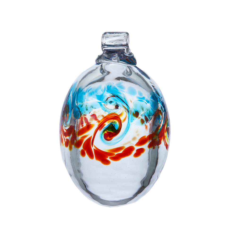 Oval glass orb with colour around the middle. Blue on top, white swirled in the middle and orange on the bottom on a transparent background.