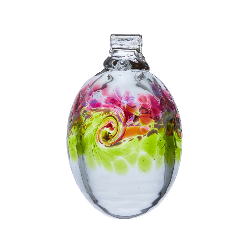 Oval glass orb with colour around the middle. Pink on top, white swirled in the middle and lime on the bottom on a transparent background.