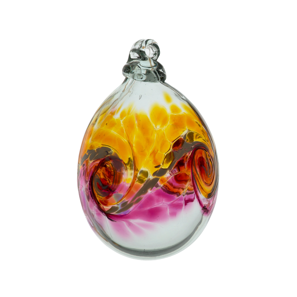 Oval glass orb with colour around the middle. Amber on top, white swirled in the middle and pink on the bottom on a transparent background.