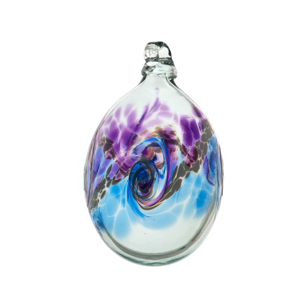 Oval glass orb with colour around the middle. Purple on top, white swirled in the middle and blue on the bottom on a transparent background.