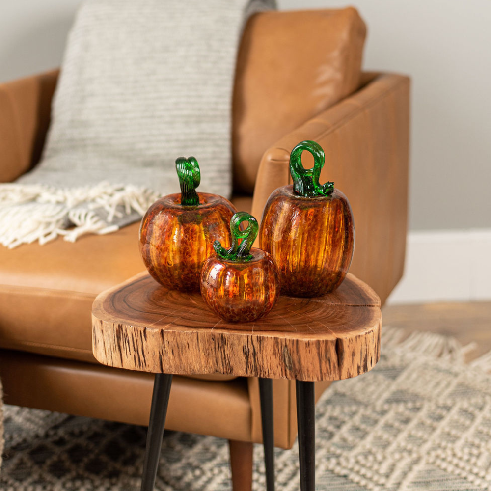 3" Round, 6" Round and Oval Rust pumpkins on a wood side table with a brown chair in the background. 