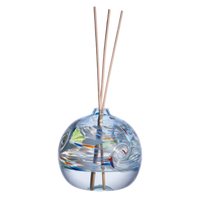 A clear glass orb with a flat bottom with white, blue, red and lime glass swirled on the top half. Orb is 1/3 full of a clear liquid and five reeds are in a hole in the top of the orb. Displayed on a transparent background.