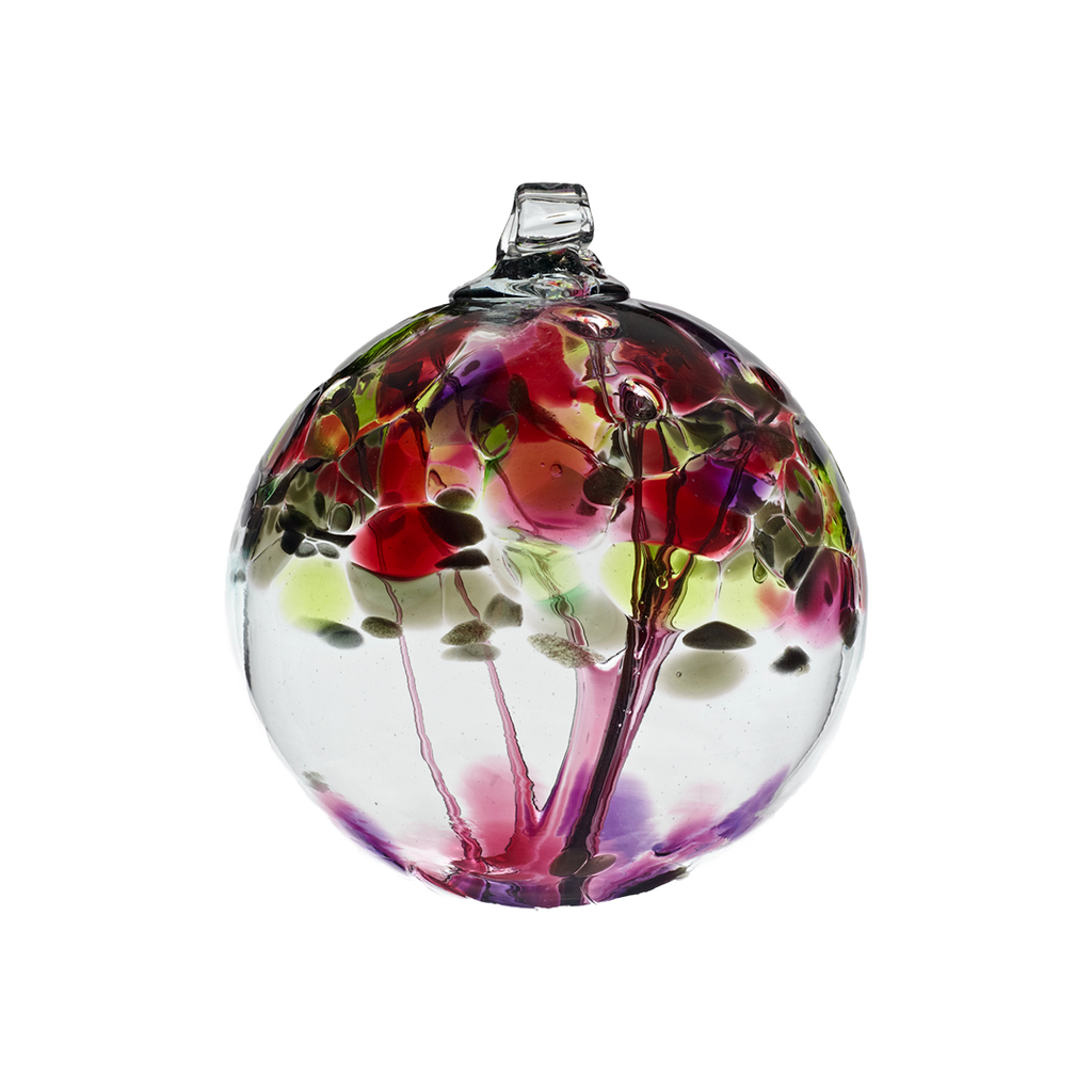 Clear glass orb with pink glass pulled through the middle and purple, pink, green and gold glitter bits on top on a transparent background.