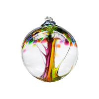 Clear glass orb with pink and orange glass pulled through the middle and yellow, purple, pink, orange and green bits on top on a transparent background.