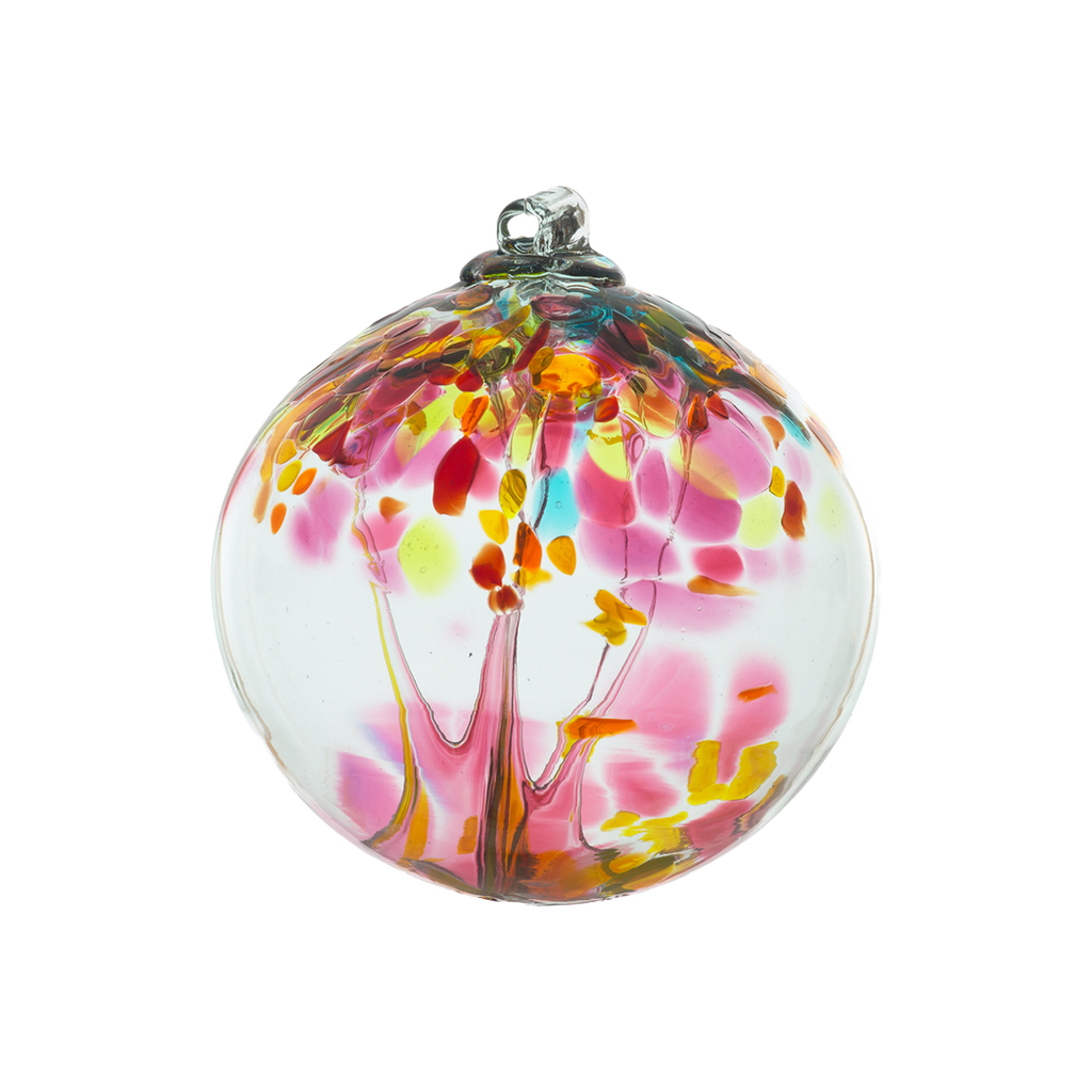 Clear glass orb with pink glass pulled through the middle and yellow, red, pink, orange and blue glass bits on a transparent background. 