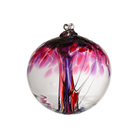 Clear glass orb with pink and purple glass pulled through the middle and red, purple and pink bits on top on a transparent background.