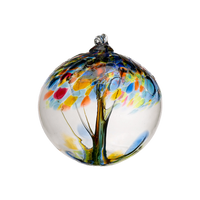 Clear glass orb with blue and orange glass pulled through the middle and yellow, red, orange and blue bits on top on a transparent background.