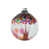 Clear glass orb with pink and orange glass pulled through the middle and yellow, red, purple, pink, orange, green and blue bits on top on a transparent background.