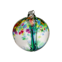 Clear glass orb with green glass pulled through the middle and red, green, lime, blue and pink glass bits on top on a transparent background. 