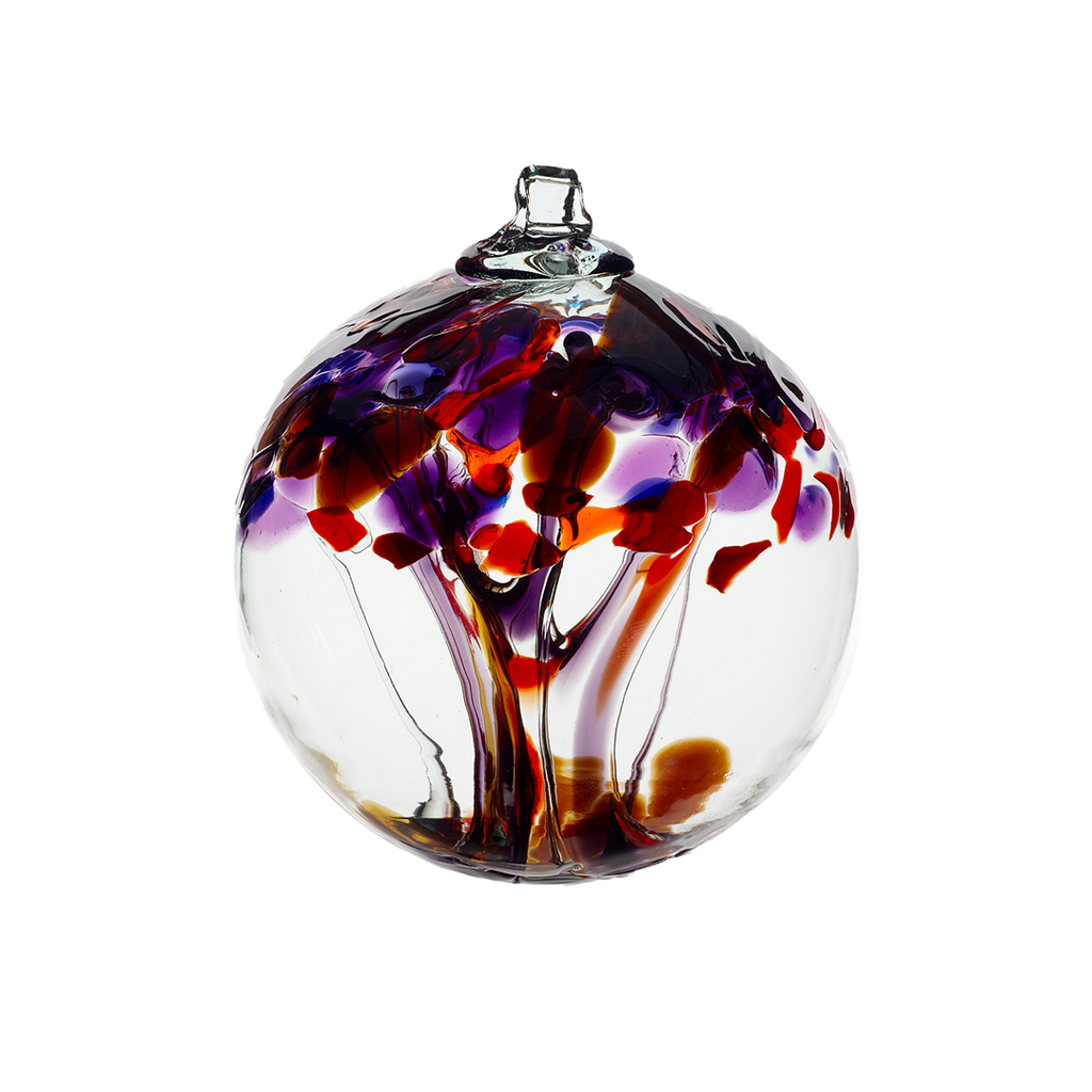 Clear glass orb with clear and purple glass pulled through the middle and red, dark purple, amethyst and brown bits on top on a transparent background.