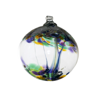 Clear glass orb with dark blue and clear glass pulled through the middle and amethyst, dark green, dark purple, amber, dark blue or gold Glitter bits on top on a transparent background.