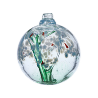 Clear glass orb with a green stem pulled from bottom to top to a canopy of blue opaque glass blossoms and orange centres on a transparent background.